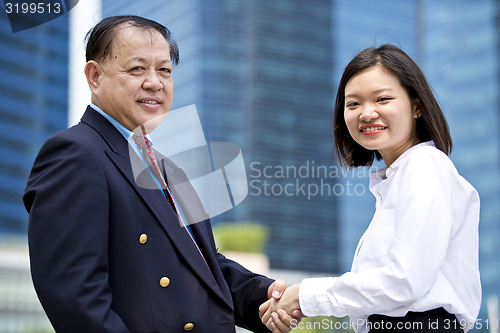 Image of Asian businessman & young female executive shaking hands