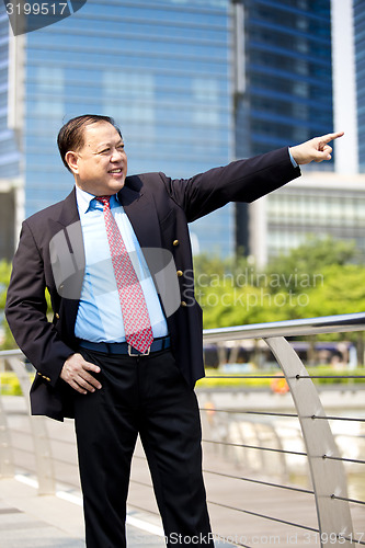 Image of Asian businessman smiling pointing at a direction