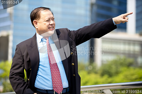 Image of Asian businessman smiling pointing at a direction