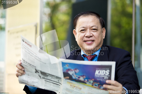 Image of Asian businessman reading newspaper