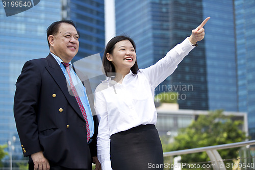 Image of Asian businessman & young female executive pointing at a direction