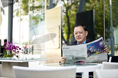 Image of Asian businessman reading newspaper