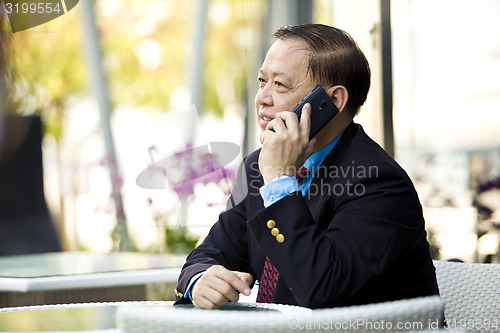 Image of Asian businessman talking on smart phone