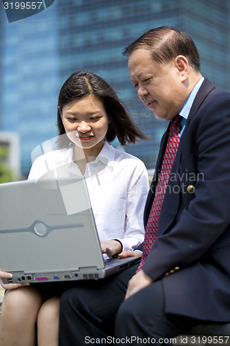 Image of Asian businessman and young female executive using laptop