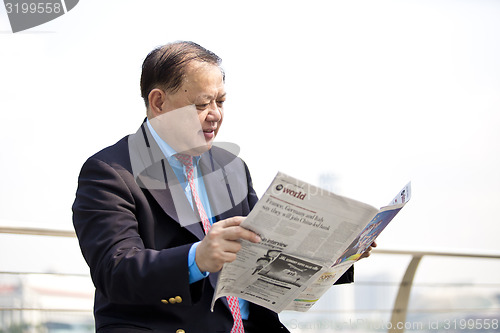 Image of Asian businessman reading newspaper