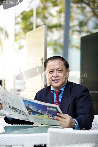 Image of Asian businessman reading newspaper