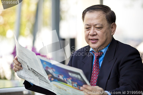 Image of Asian businessman reading newspaper
