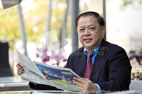 Image of Asian businessman reading newspaper