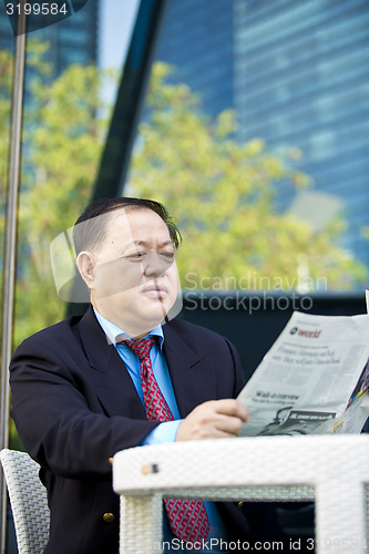 Image of Asian businessman reading newspaper