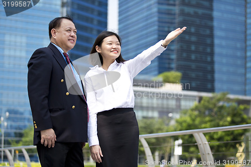 Image of Asian businessman and young female executive pointing at a direction