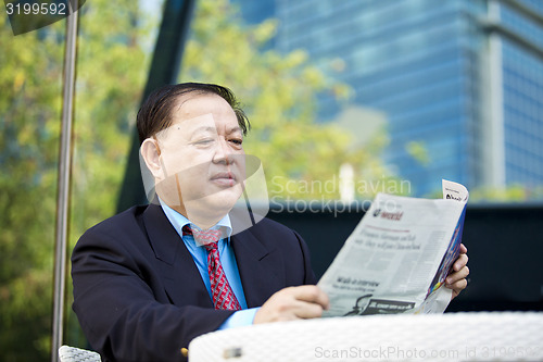 Image of Asian businessman reading newspaper