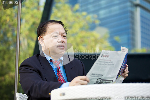 Image of Asian businessman reading newspaper