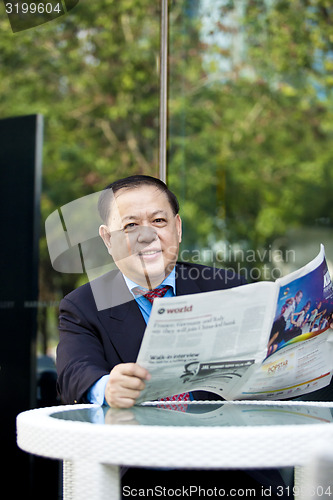 Image of Asian businessman reading newspaper