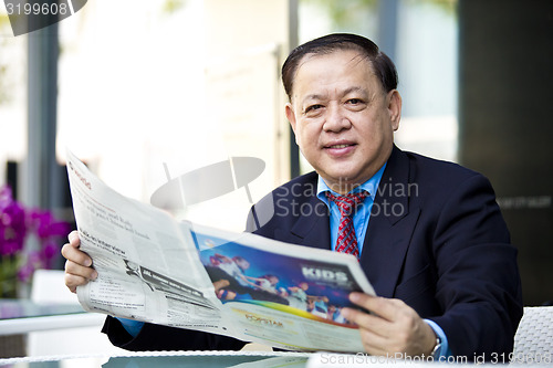 Image of Asian businessman reading newspaper