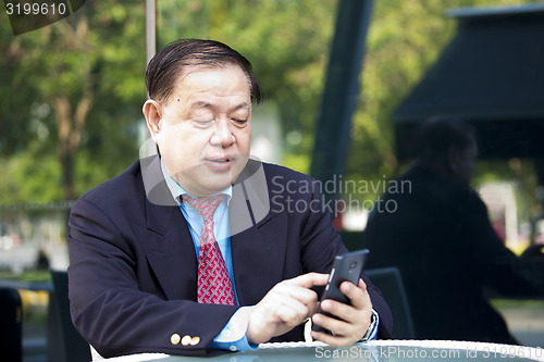 Image of Asian businessman looking at smart phone