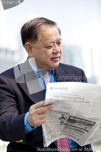 Image of Asian businessman reading newspaper