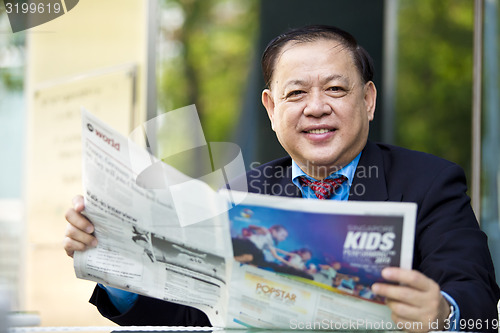 Image of Asian businessman reading newspaper