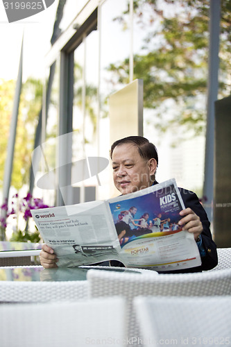 Image of Asian businessman reading newspaper