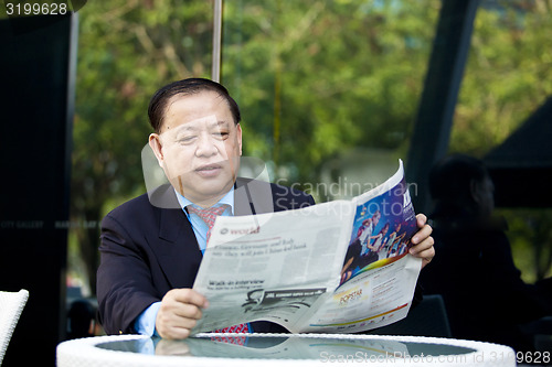 Image of Asian businessman reading newspaper