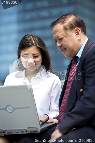 Image of Asian businessman and young female executive using laptop