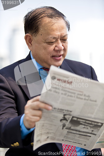 Image of Asian businessman reading newspaper