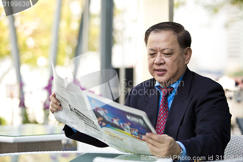 Image of Asian businessman reading newspaper