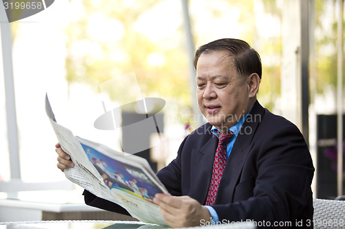 Image of Asian businessman reading newspaper