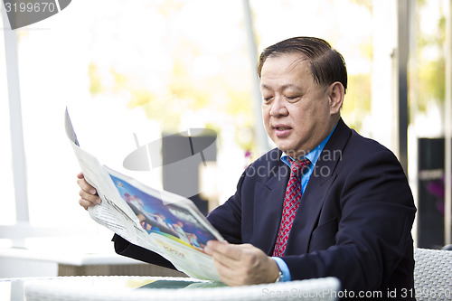 Image of Asian businessman reading newspaper