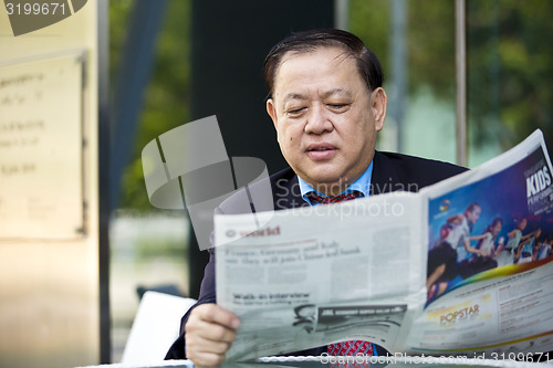 Image of Asian businessman reading newspaper