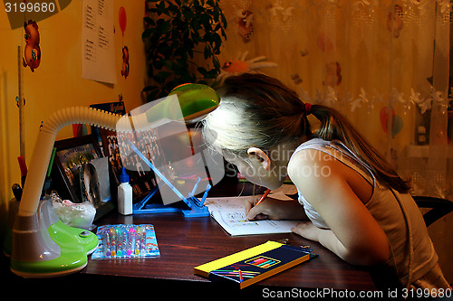 Image of schoolgirl learns lessons at the table