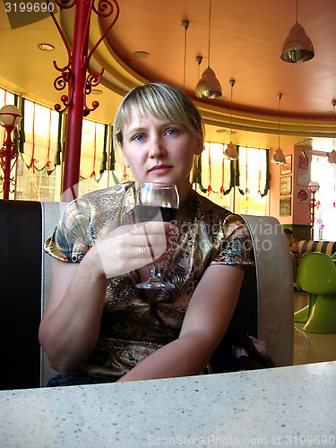 Image of glass of red wine on the table and women