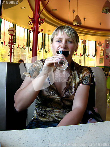 Image of glass of red wine on the table and a girl