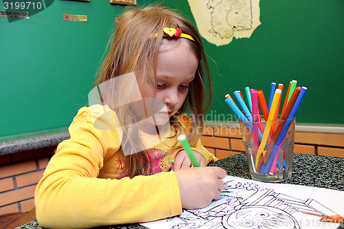 Image of little girl draws the drawing at the table