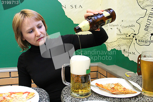 Image of woman pouring beer in a glass and pizza