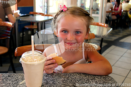 Image of little beautiful girl having dinner in café