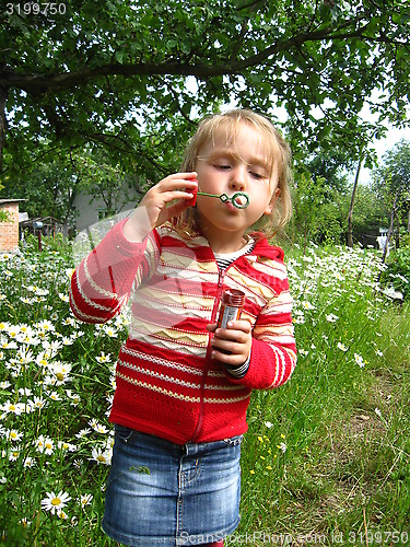 Image of little girl swelling soap bubbls in chamomiles