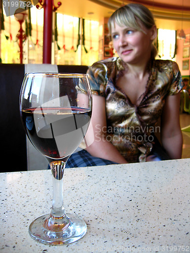 Image of glass of red wine on the table and a girl