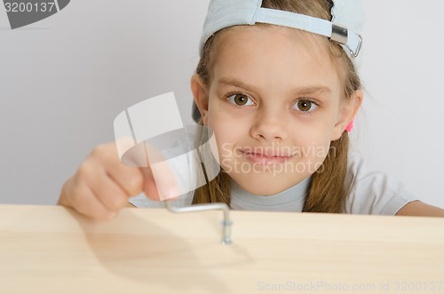 Image of Girl twists the screw with an Allen key