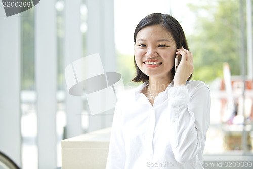 Image of Asian young female executive talking on smart phone
