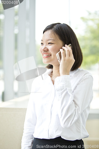 Image of Asian young female executive talking on smart phone