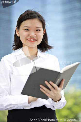 Image of Asian young female executive holding book smiling