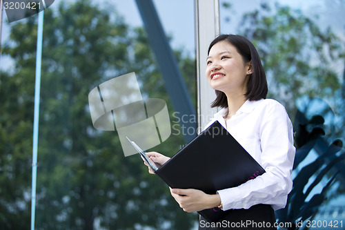 Image of Asian young female executive holding file smiling