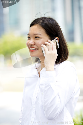 Image of Asian young female executive talking on smart phone