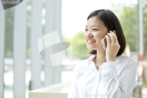 Image of Asian young female executive talking on smart phone