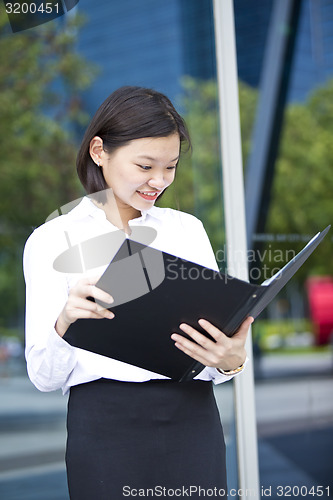 Image of Asian young female executive holding file smiling