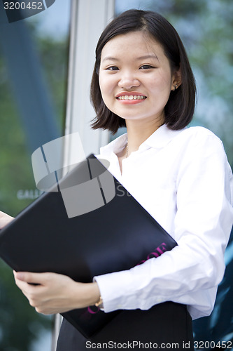 Image of Asian young female executive holding file smiling