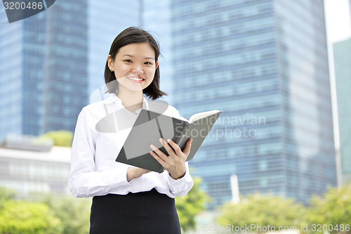 Image of Asian young female executive holding book smiling