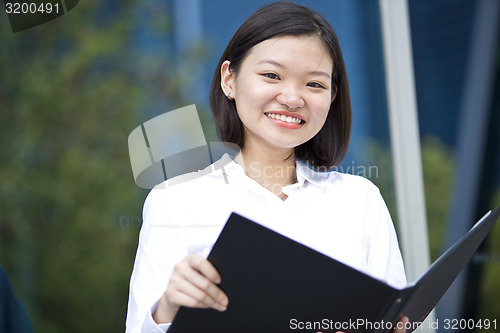 Image of Asian young female executive holding file smiling