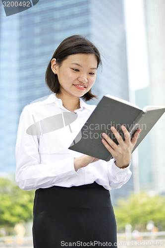 Image of Asian young female executive holding book smiling