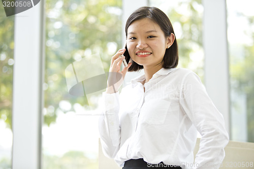 Image of Asian young female executive talking on smart phone